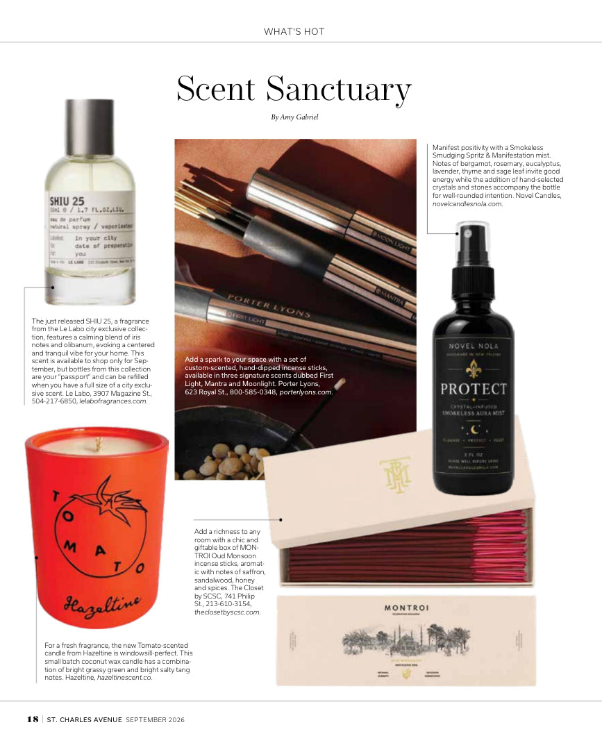 A New Orleans Magazine product spread titled 'Scent Sanctuary' featuring multiple fragrance and home fragrance items: a clear bottle labeled SMY 25, a dark bottle labeled NOVEL NOVA PROTECT CRYSTAL INFUSED ROOM SPRITZ BODY & LINEN SPRAY, a red candle jar with 'TOMATO' and 'Hazelrigg' text, a pink striped candle, and a Montei candle box. There are also close-up photos of diffuser wicks and a candle flame, with small caption blocks and a magazine footer.