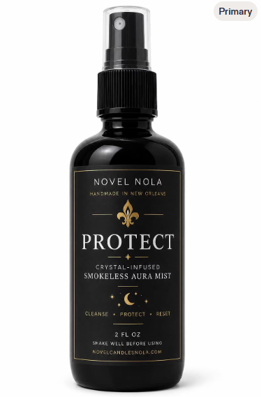 A 2 FL OZ black spray bottle of Novel Nola Protect Crystal-Infused Smokeless Aura Mist, featuring a black label with gold and white text and graphics, on a white background.
